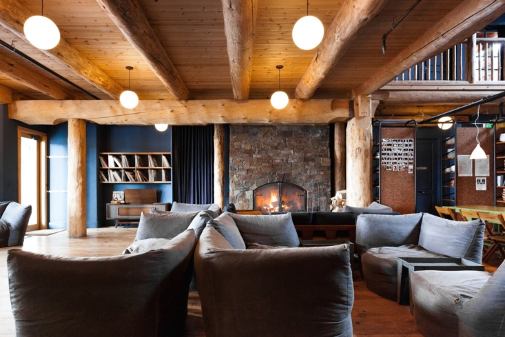 Inside the Lodge are lounging essentials—a large cozy fireplace; comfortable, low pouf seating; and the requisite hipster accessories, a vintage record player and some vinyl. Globe pendant lights are by Schoolhouse.